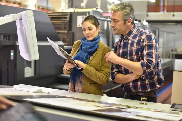 Man in printing house showing client printed documents translated into his native language 