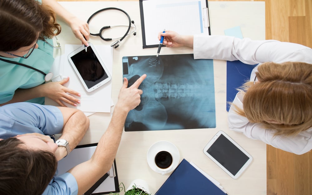 Médicos sentados alrededor de una mesa mirando una imagen de rayos X-3