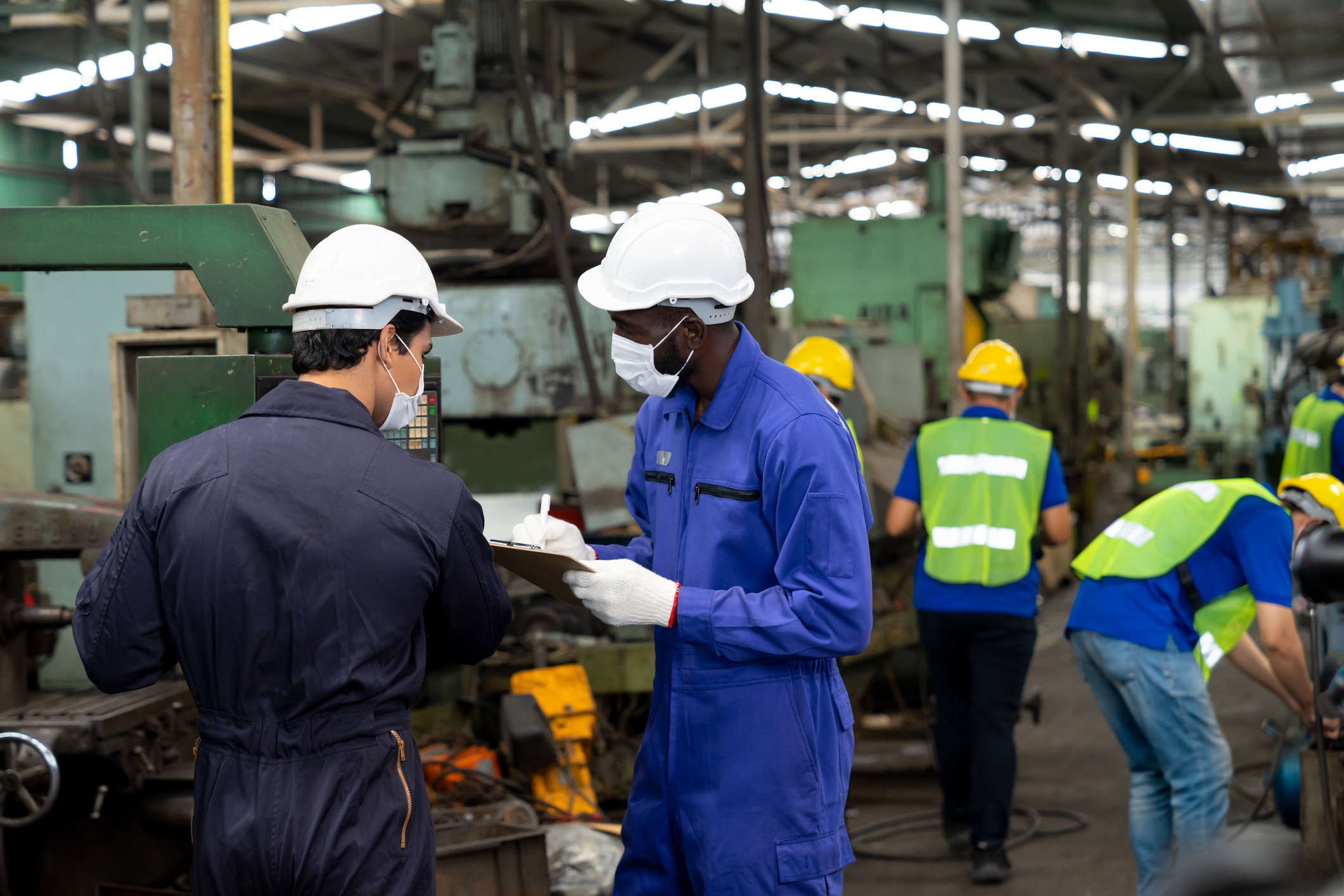 An image of a group of multicultural manufacturing workers reading manuals in their native language made possible through machine translation